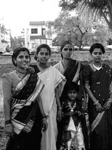 four women in saris (dresses) stand for the camera