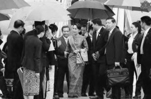 a group of people face a woman as she walks out of a building