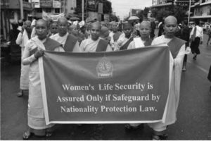 a group of people walk with a banner saying "women's life security is assured only if safeguard by nationality protection law"