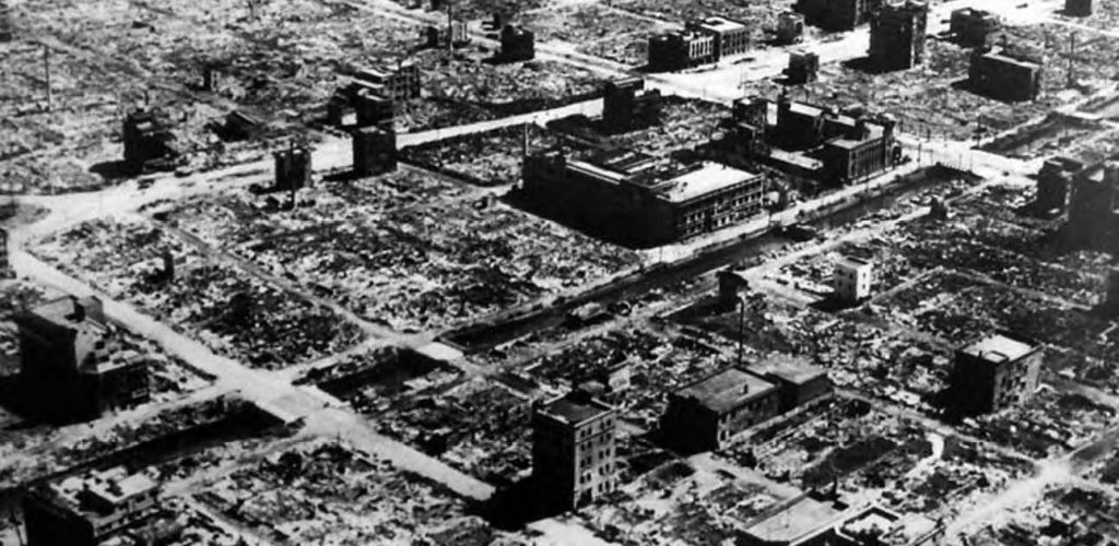 aerial photo of where a city once was. you can see where the remnants of burned houses were, with only a few buildings sporadically standing amidst burnt rubble.