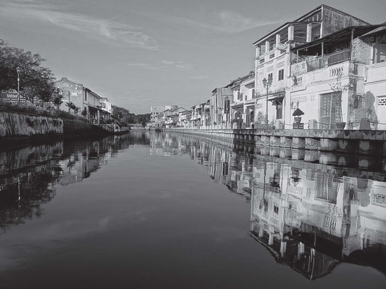 photo of a canal with buildings on one side and a park on the other