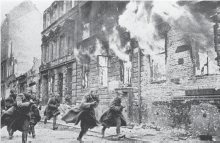A harrowing image depicting buildings and houses engulfed in flames in a Jewish neighborhood. In the foreground, five individuals can be seen running away from the fire, capturing the urgency and devastation of the scene.