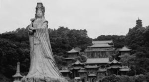 photo of a statue of a woman in robes in front of a large temple complex