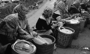photo of women sitting in front of baskets of sticky rice