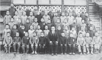 Photograph of elementary school boys posing for a school photograph in five neat rows. Hirano stands in the second row and face is circled. 